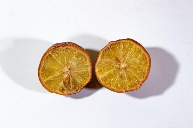 rotten lemon cut into two halves on a plain white background