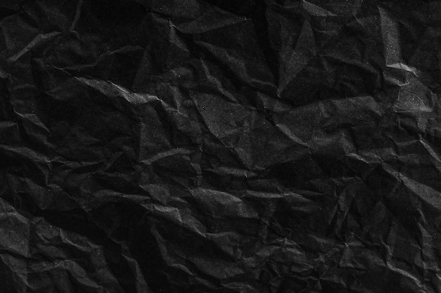 Rough damaged crumpled black paper texture background with wrinkles