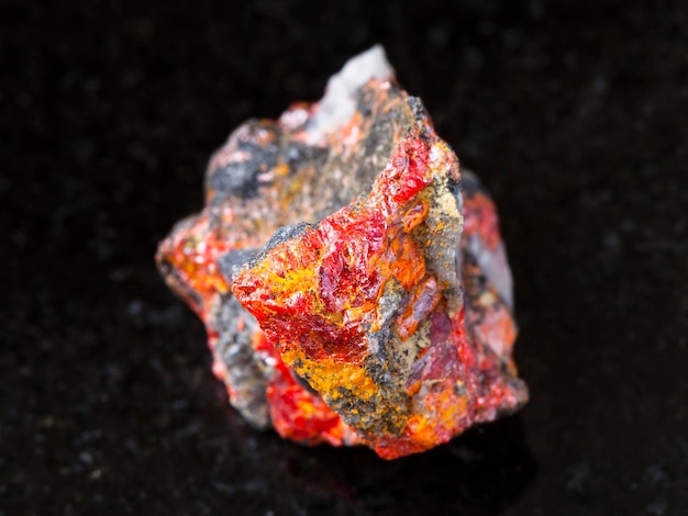 Rough Realgar crystals on stone on dark