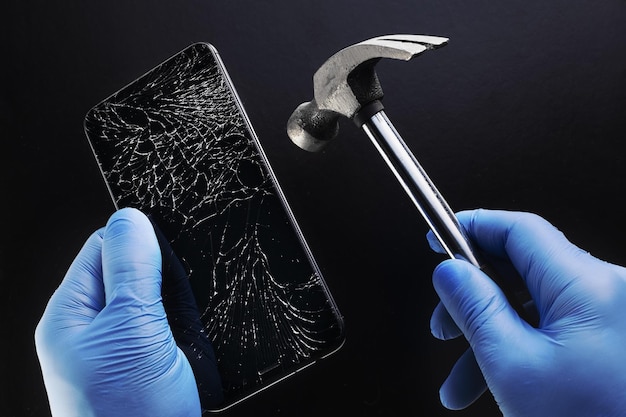 Rough repair the phone a smartphone with a cracked display and\
a hammer in the hands of a master