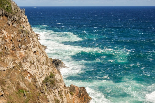 rough sea waters crash violently against rock cliff on the coast