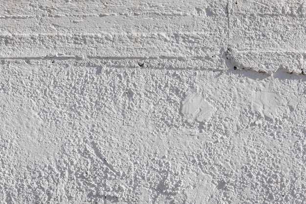 Rough whitewash or white plaster wall under direct sunlight fullframe background and texture