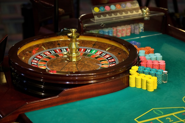 Рулетка и зеленый стол с фишками в казино