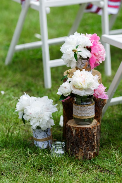 Round arch made of wooden branches, decorated with a lot of peonies and roses. Spring wedding floristics in white and pink colors, rustic style