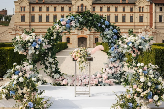 A round arch for the painting of the newlyweds decorated with greenery blue pink and white flowers