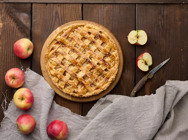 Round baked apple pie on a brown wooden table top view