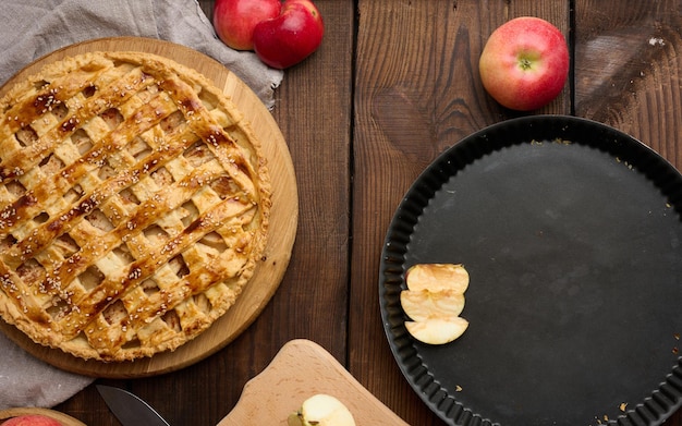 Round baked apple pie on a brown wooden table top view