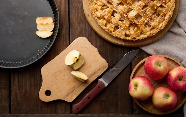 Round baked apple pie on a brown wooden table top view