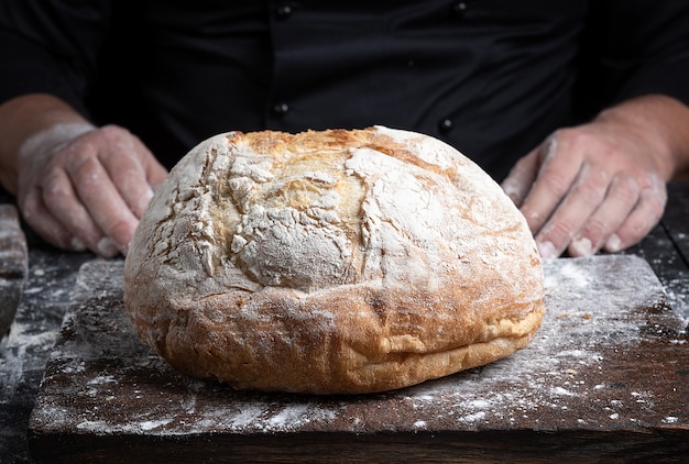 Round baked homemade bread on an old brown wooden board