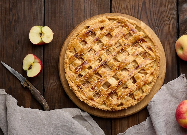 사진 나무 판자 갈색 테이블에 사과를 채운 둥근 구운 파이