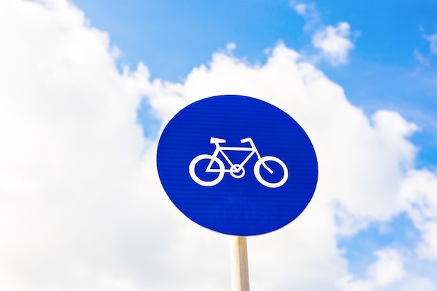 Round bicycle lane sign against a blue sky