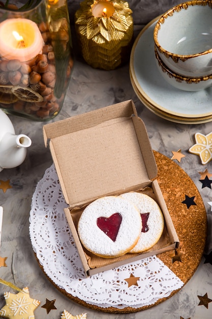 Biscotti rotondi con marmellata a forma di cuore in confezione regalo tra le decorazioni natalizie