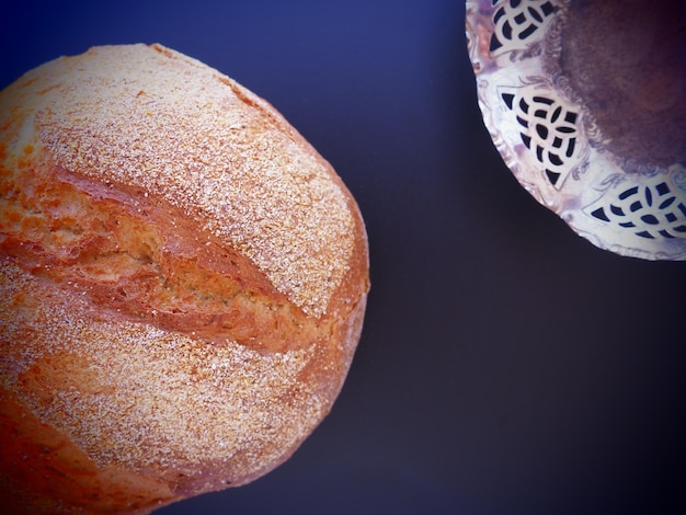 丸いパンの上面図青い背景に振りかけるおいしい新鮮なコーンブレッド金属銀皿の側面図コピースペース伝統的なレシピ手作りのパンとキャンディーボウル