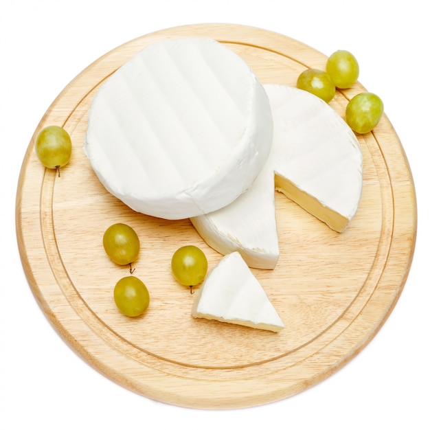 Round brie or camembert cheese on cutting board white table