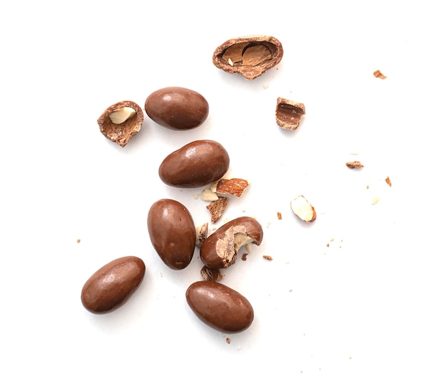 Round and broken small chocolate candies with almond nuts as filling isolated on white top view