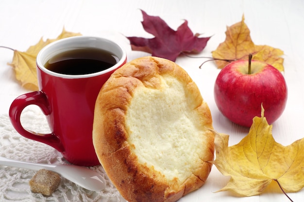 Round bun with cottage cheese and cup of tea on table