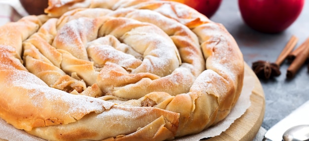 Round burek pie with an apple on a dark background. Traditional Serbian cuisine. Selective focus. Top view.