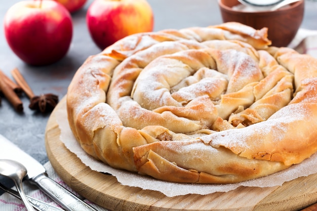 어두운 배경에 사과와 둥근 burek 파이. 세르비아 전통 요리. 선택적 초점. 평면도.