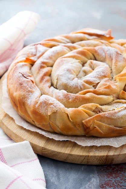 Torta rotonda del burek con una mela su un fondo scuro. cucina serba tradizionale. messa a fuoco selettiva. vista dall'alto.