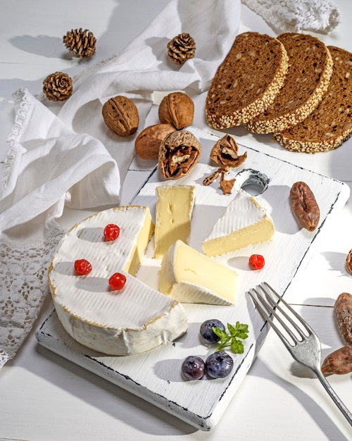 Round Camembert cheese on white wooden board