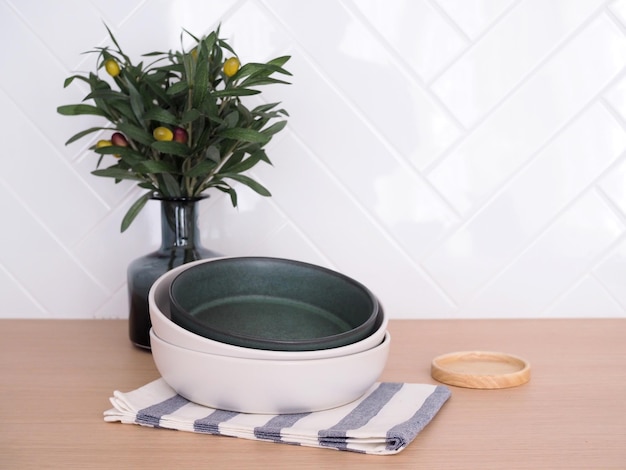 Round ceramic tableware set on cloth on wooden top with wood coasters and plants in glass vase