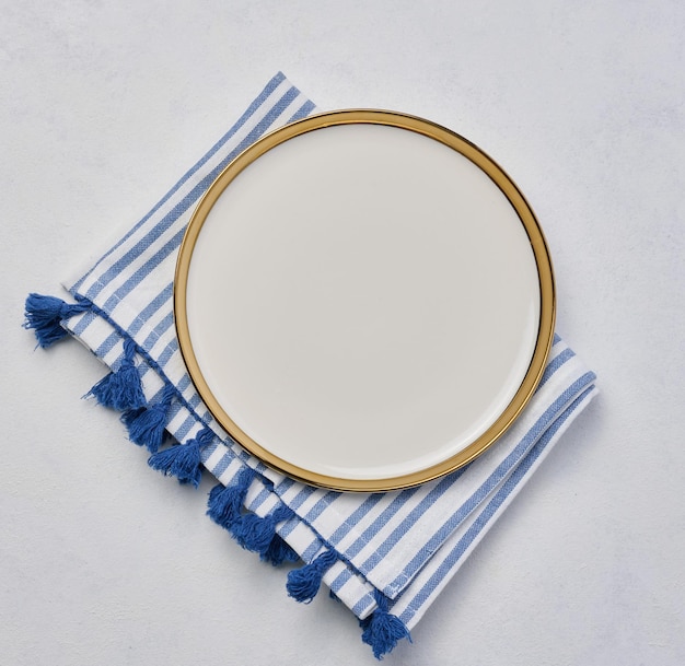 Round ceramic white plate with a gilded edge on a white background top view