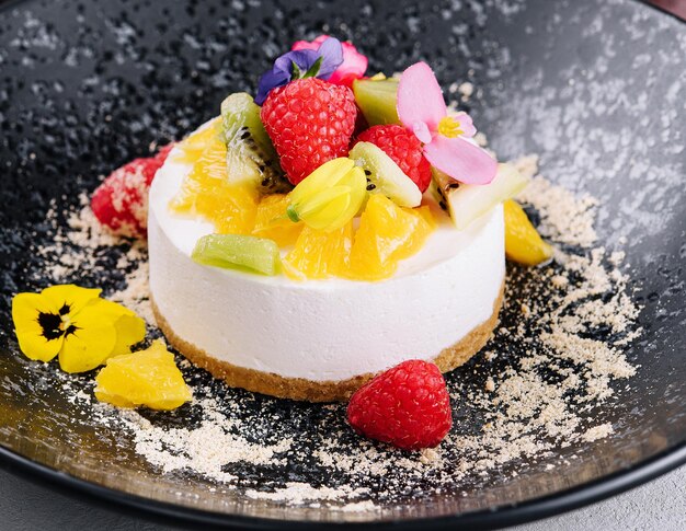 Round cheesecake with fruit decoration and cup of coffee