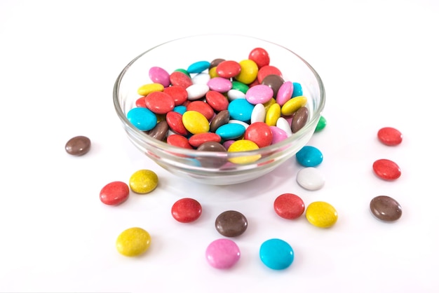 Круглые цветные конфеты в тарелке на белом фоне