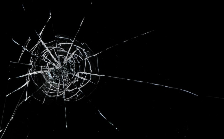 Round cracks in glass on black background. The hole in the glass surface from the bullet.