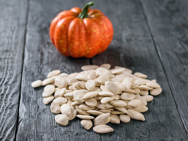 Round decorative pumpkin and a bunch of pumpkin seeds on a rustic table