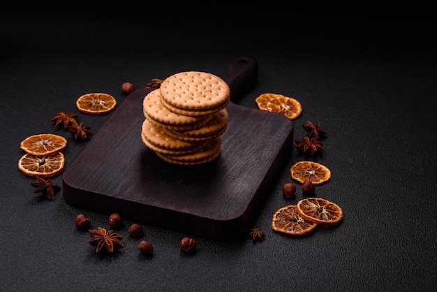 Round dotted snack snack cookies with cream on a dark concrete background