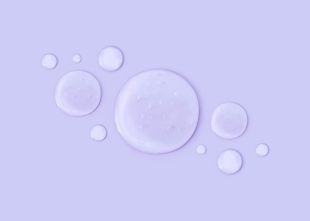 Round drops of transparent gel serum on a pastel background