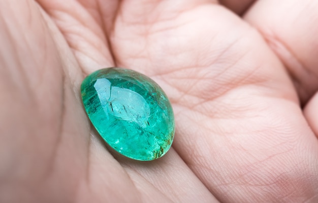 The round emerald gemstone in hand.