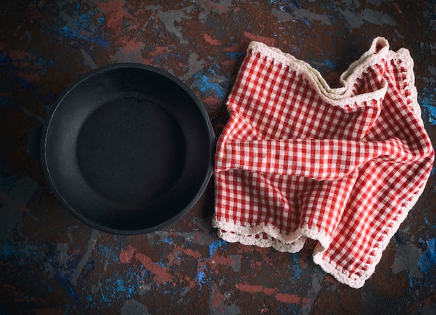 Round empty black cast-iron frying pan with a red napkin in a red box 