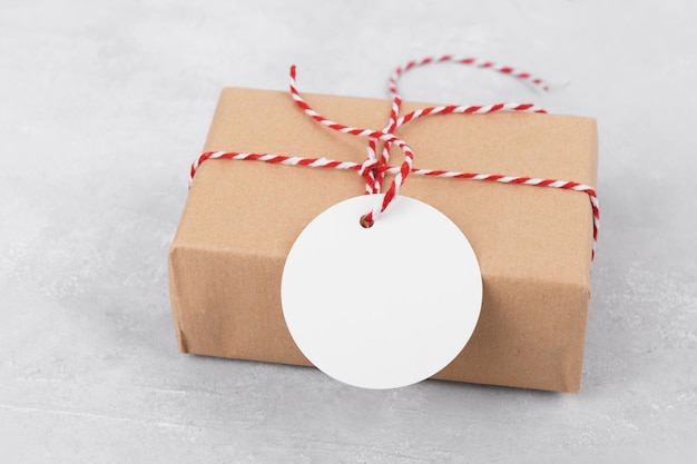 Round empty gift tag mockup on gift kraft box on grey background