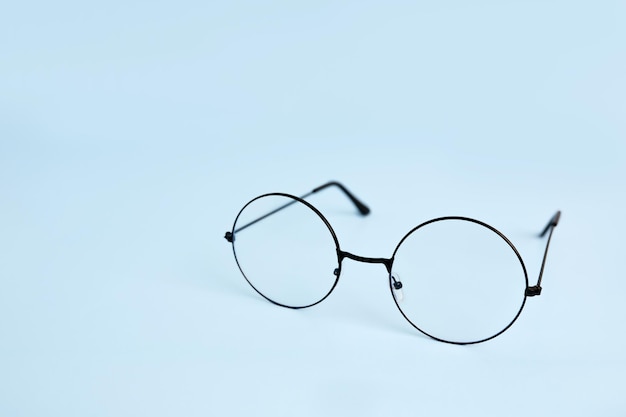 Round eyeglasses for vision on a blue background with space for text