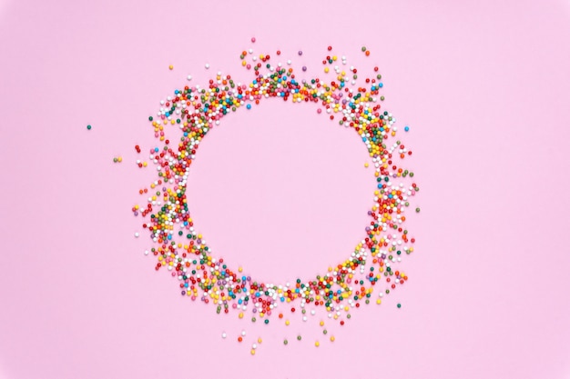 Round frame of colored sweets on a pastel colored background. 