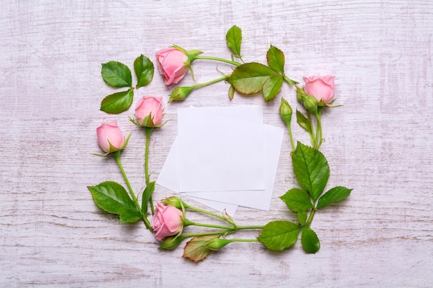 Round frame of delicate flowers Pink roses on a wooden background Paper with empty place for text