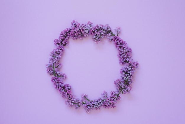 Round frame of lilac flowers on a lilac background Copy space flat lay