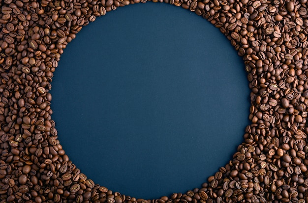 Round frame made from coffee beans on black background. gorizontal arrangement. top view. copy space for text.