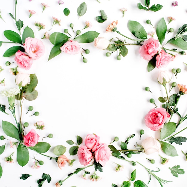 ピンクとベージュのバラ、緑の葉、枝、白の花柄で作られた丸いフレーム