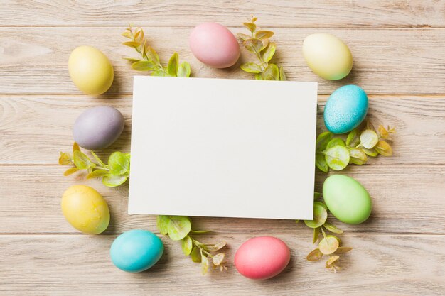 Round frame multicolored Easter eggs with white blank paper on a brown background closeup space for text blank for design selective focus tinted image