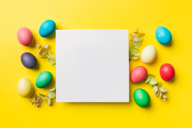 Round frame multicolored Easter eggs with white blank paper on a brown background closeup space for text blank for design selective focus tinted image