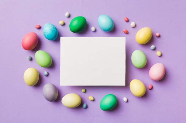 Round frame multicolored Easter eggs with white blank paper on a brown background closeup space for text blank for design selective focus tinted image