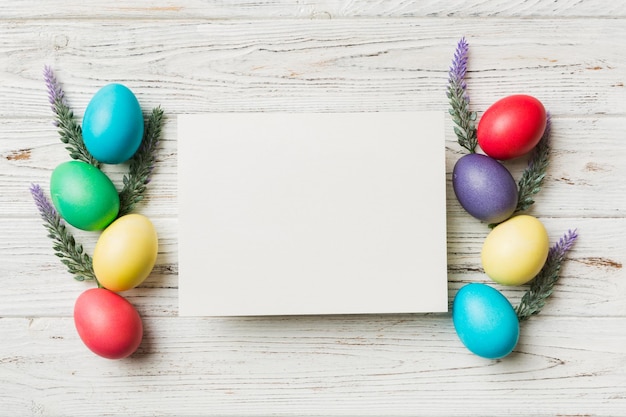 갈색 배경 근접 촬영 공간에 흰색 빈 종이가 있는 원형 프레임 여러 가지 빛깔의 부활절 달걀