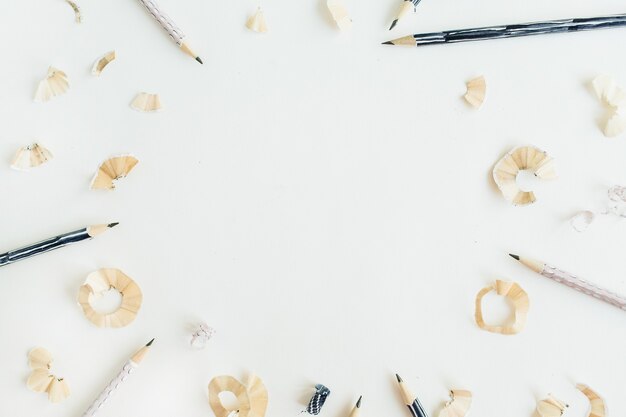 Round frame of pencils and shavings on white surface