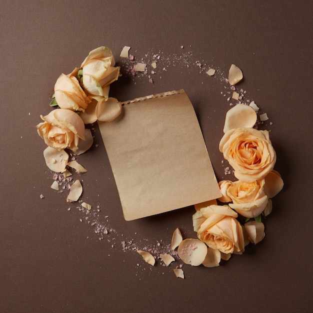 Круглая рамка из роз на коричневом фоне с листом бумаги для текста, плоская планировка