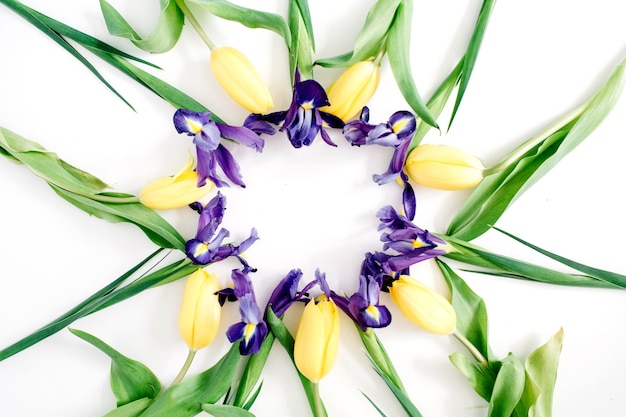 Round frame wreath made of yellow tulips and purple iris flowers on white