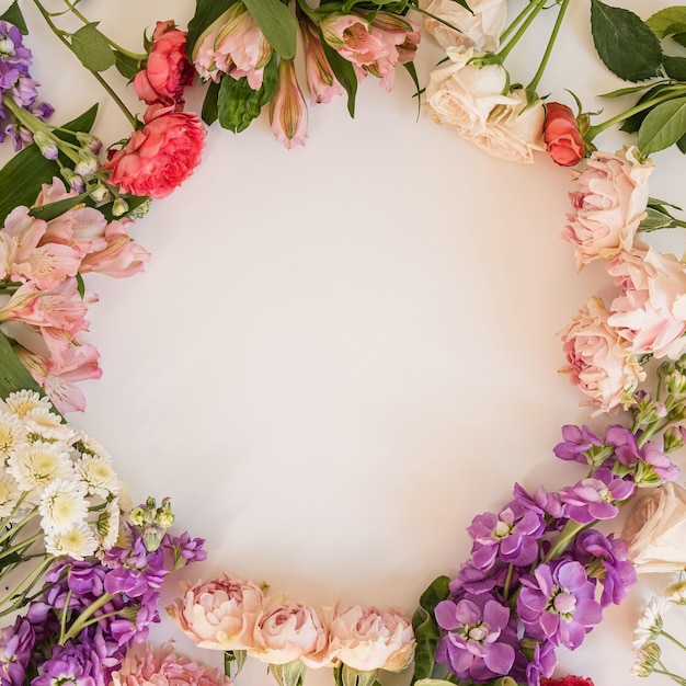 Round frame wreath pattern with roses pink flower buds branches and leaves isolated on white background Flat lay top view Aesthetic floral template with blank space