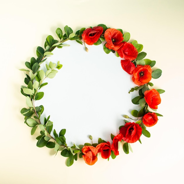 Round frame wreath with red poppies bloom and branches on sandy background Minimal floral composition Flat lay Copy space